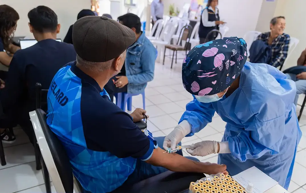Voluntarios de Noviembre Azul orientando a hombres mayores en una campaña de prevención del cáncer de próstata